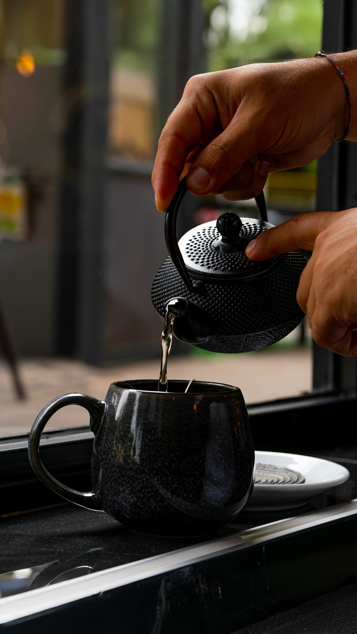 A serene moment of tea being poured into a cup by a window in a cozy café.