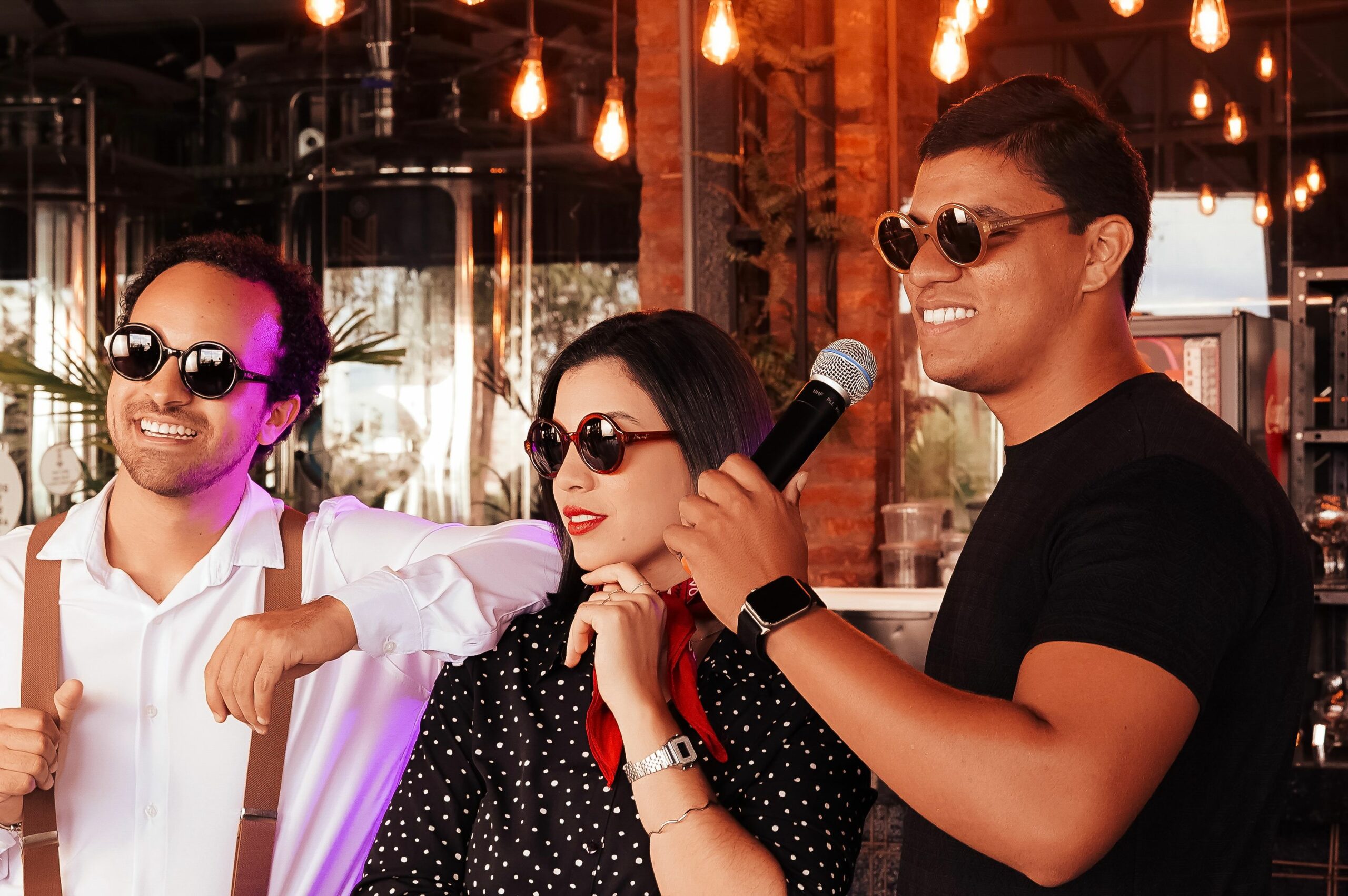 Three friends enjoying a karaoke session indoors with vintage decor and warm lighting.